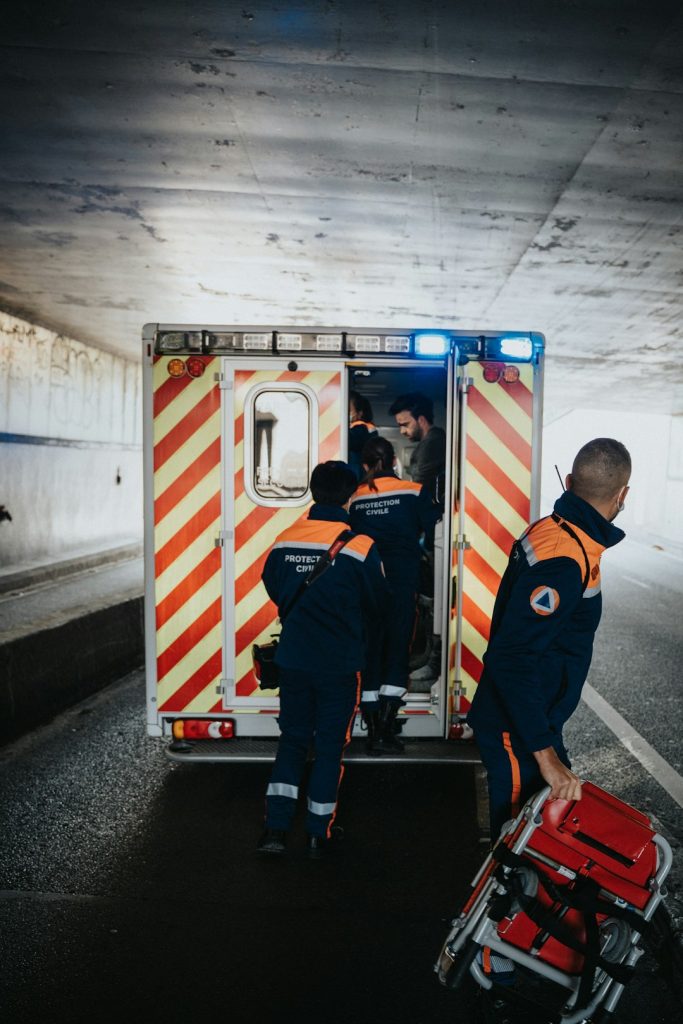 a-couple-of-men-standing-next-to-an-ambulance-ygyp2kxy2i0